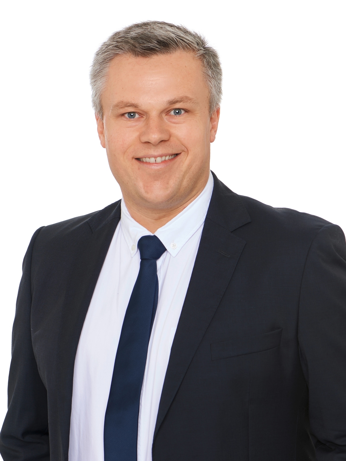 Portrait Florian Heitzmann. Lächelnder Mann mit weißem Hemd, schwarzem Jackett und Krawatte. 