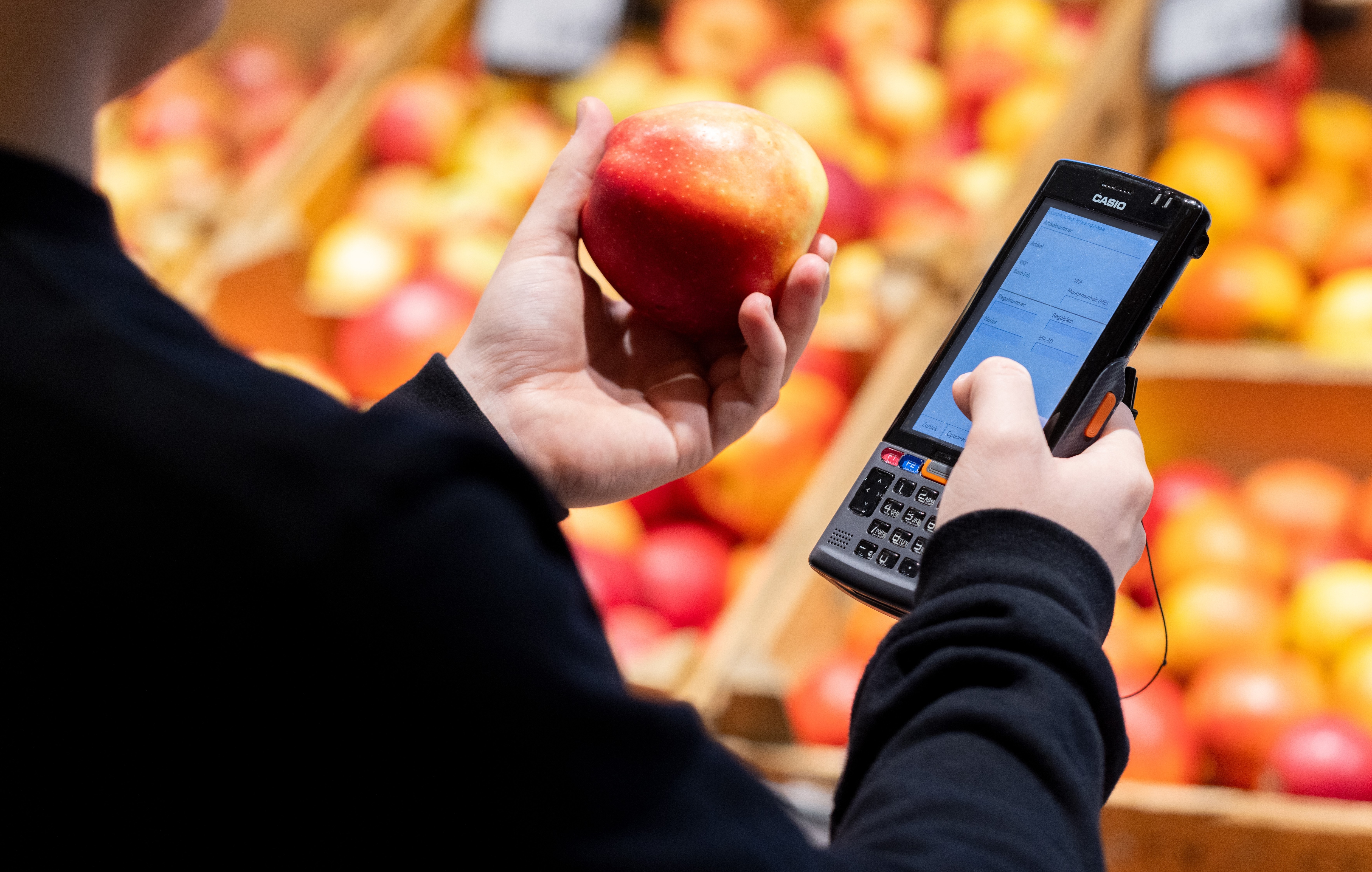 Mitarbeiterin hält einen Apfel und MDE Gerät in der Hand.