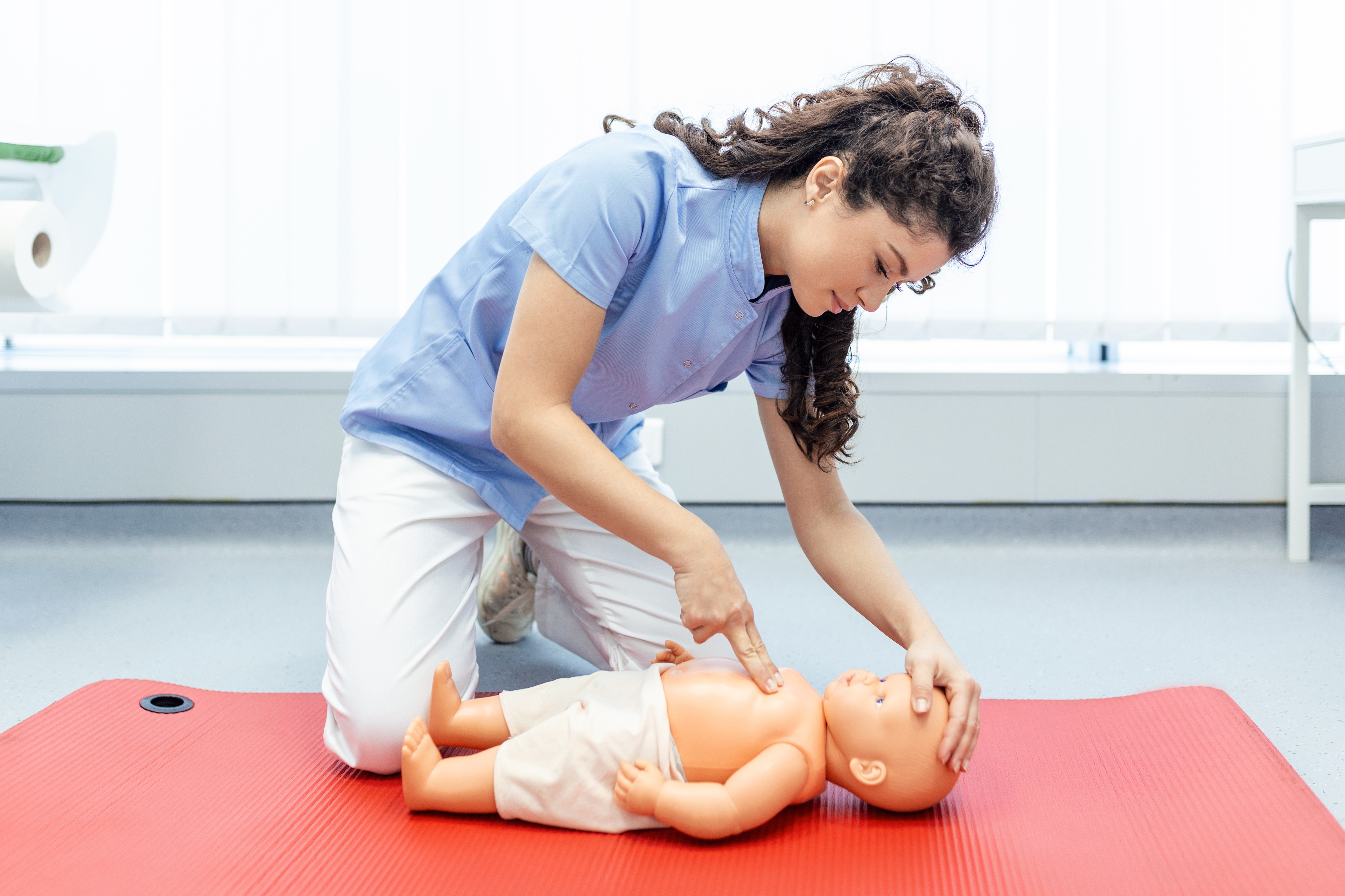 Frau führt Herzdruckmassage an einer Baby Atrappe durch. 