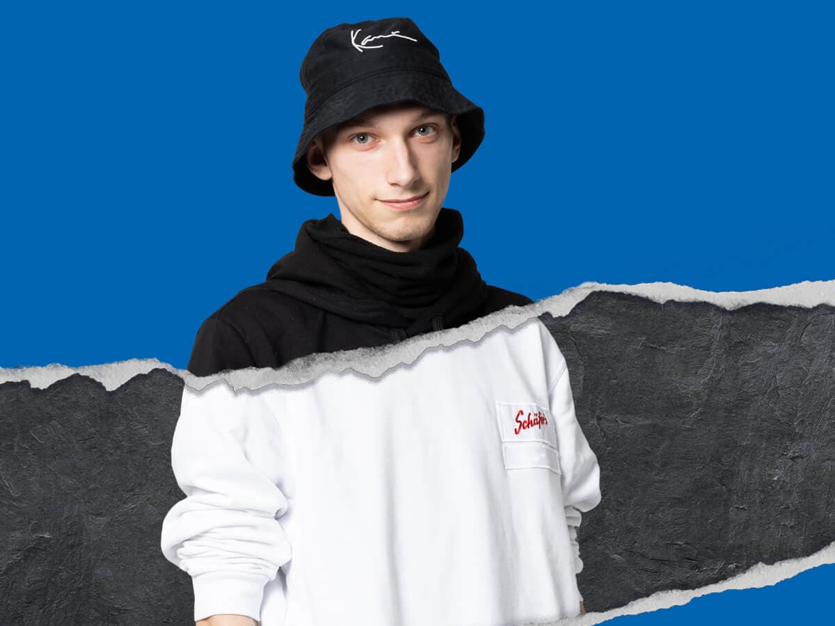Azubi aus der Produktion vor blauem Hintergrund und mit Risskante
