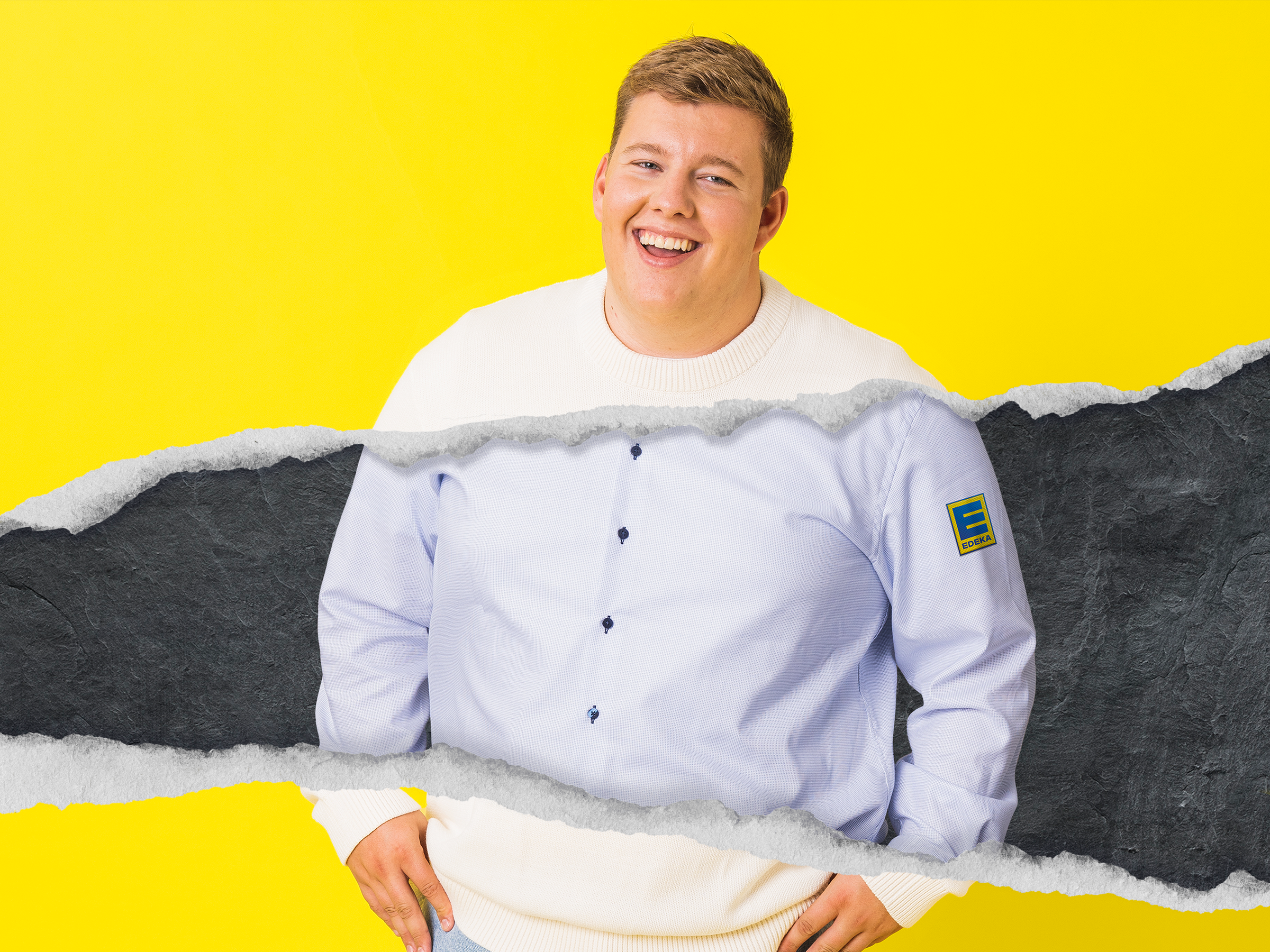 Junger blonder Mann in weißerm EDEKA-Hemd.