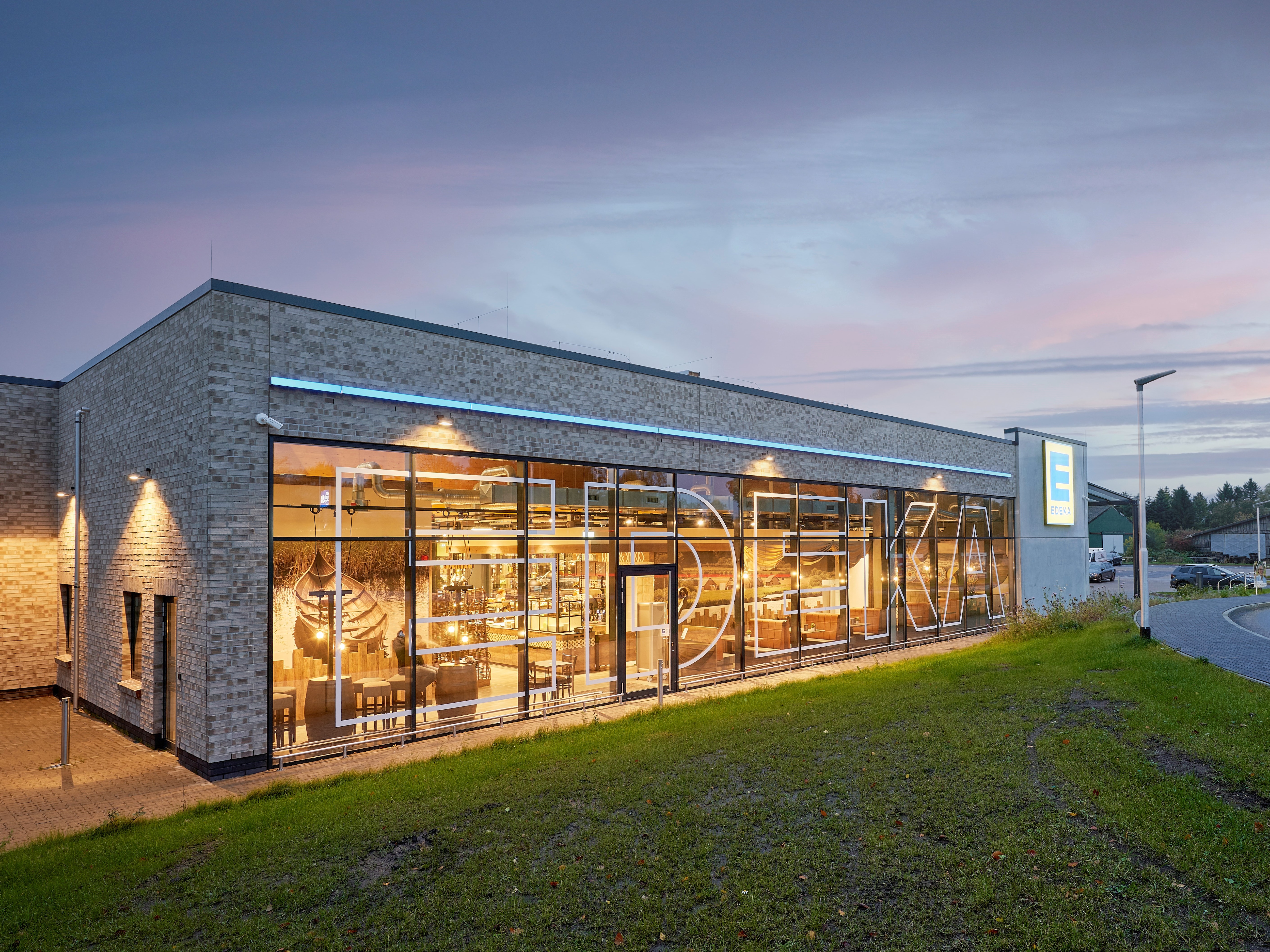 Luftaufnahme eines modernen EDEKA-Marktes mit Glasfront in der Abenddämmerung