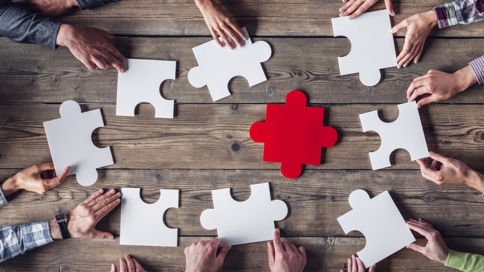 Puzzleteile und viele Hände