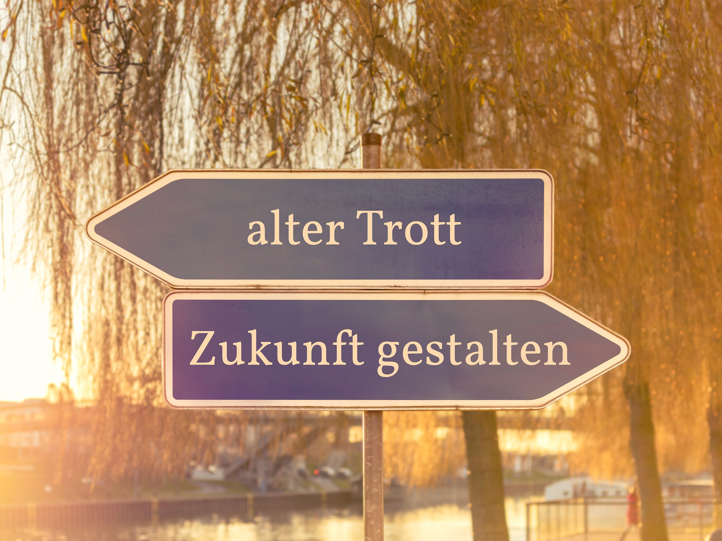 2 Schilder stehen draußen in entgegengesetzter Richtung: auf einem steht "alter Trott" auf dem anderen " Zukunft gestalten"