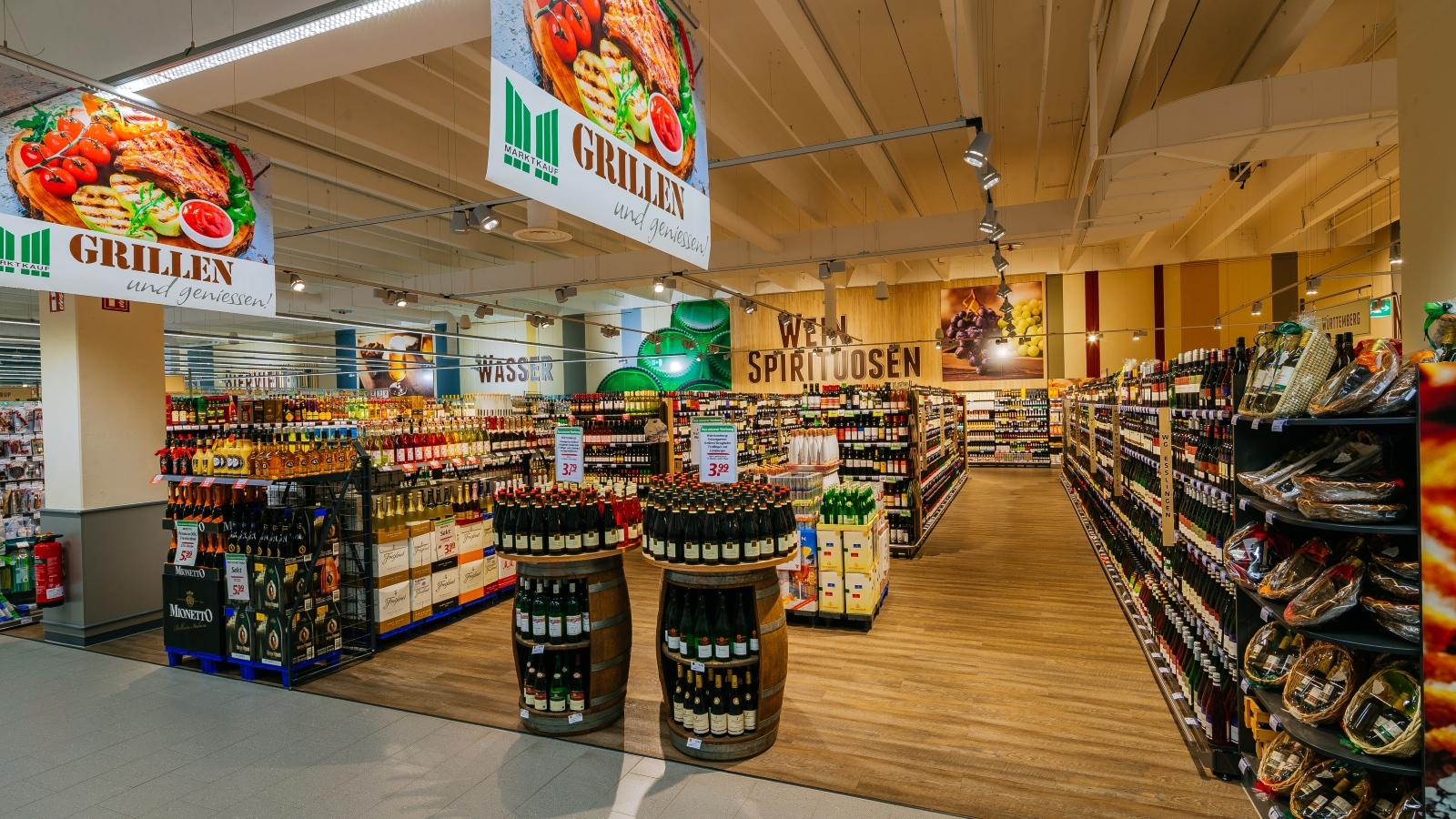  Marktkauf-Markt: Blick in die Weinabteilung mit Weinregalen, Holzfässern, Holzboden und Holzdecke.