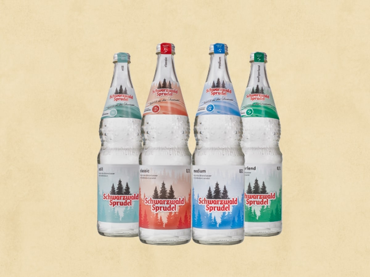 4 Flschen Mineralwasser von SchwarzahlSprudel, je nach Sorte ist das Etikett in Blau-, Grün-, Rot- oder Salbeitönen gehalten.