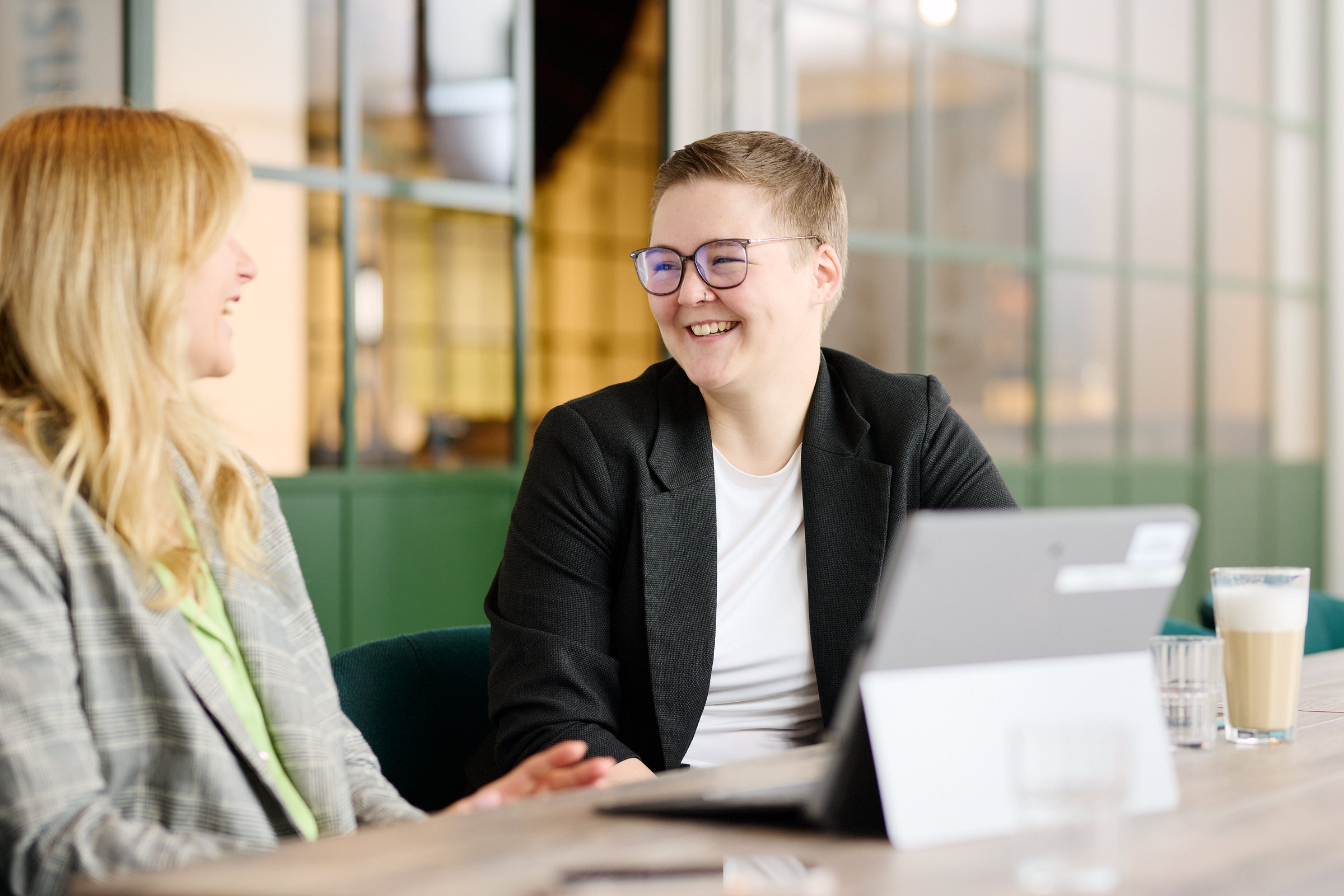 Zwei Trainees im Gespräch, beide lachen. 