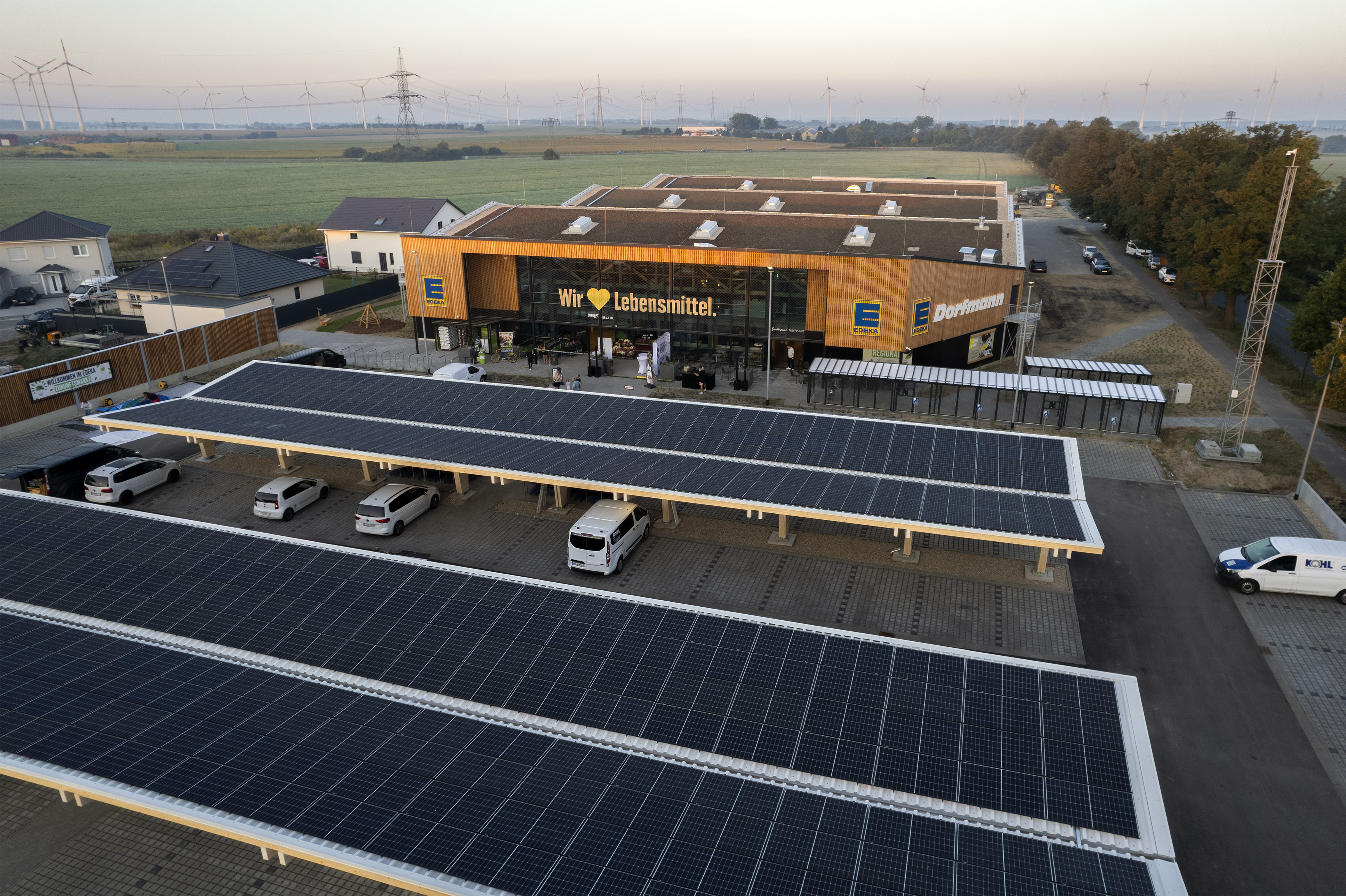 Der Zukunftsmarkt EDEKA Dorfmann in Nauen zeigt sich mit einer Holzfassade und Photovoltaik-Carports auf dem Parkplatz.