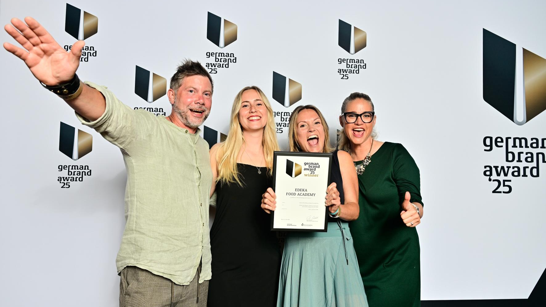 Ein Mann und 3 Frauen stehen vor einer Preisverleihungswand. Eine davon hat die Urkunde zum German Brand Award in der Hand.