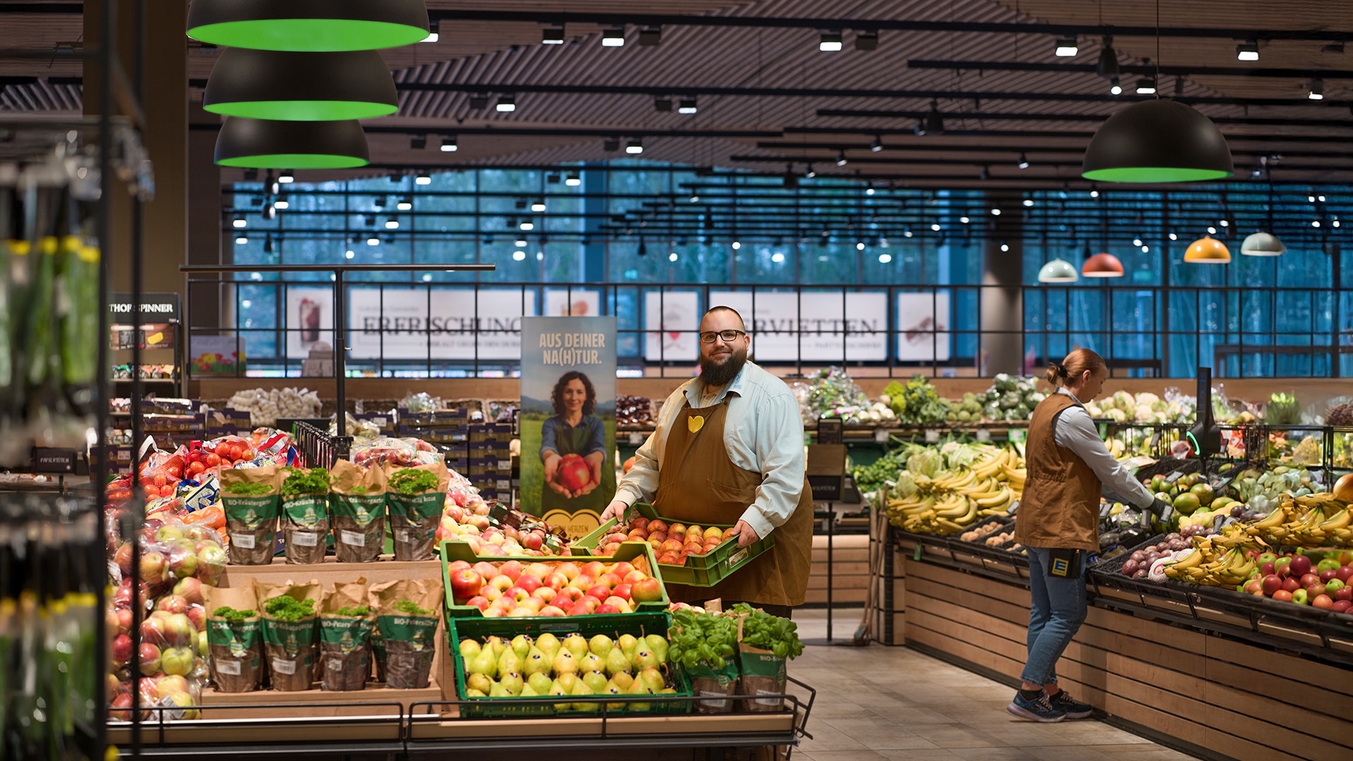 Zwei EDEKA-Mitarbeitende räumen in der Obst- und Gemüseabteilung Waren in die Auslage. 