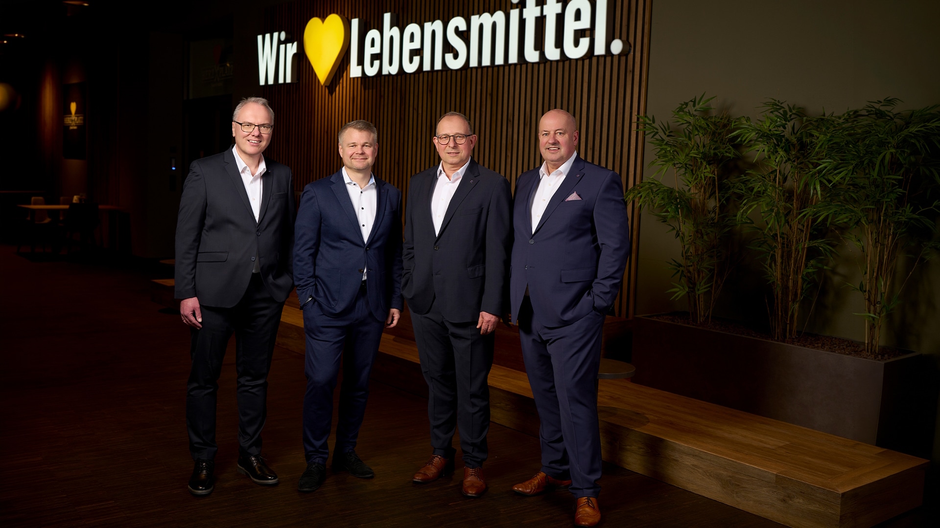 Gruppenfoto des vierköpfigen Vorstands von EDEKA Südwest vor einer Wand mit dem Marken-Claim "Wir lieben Lebensmittel".