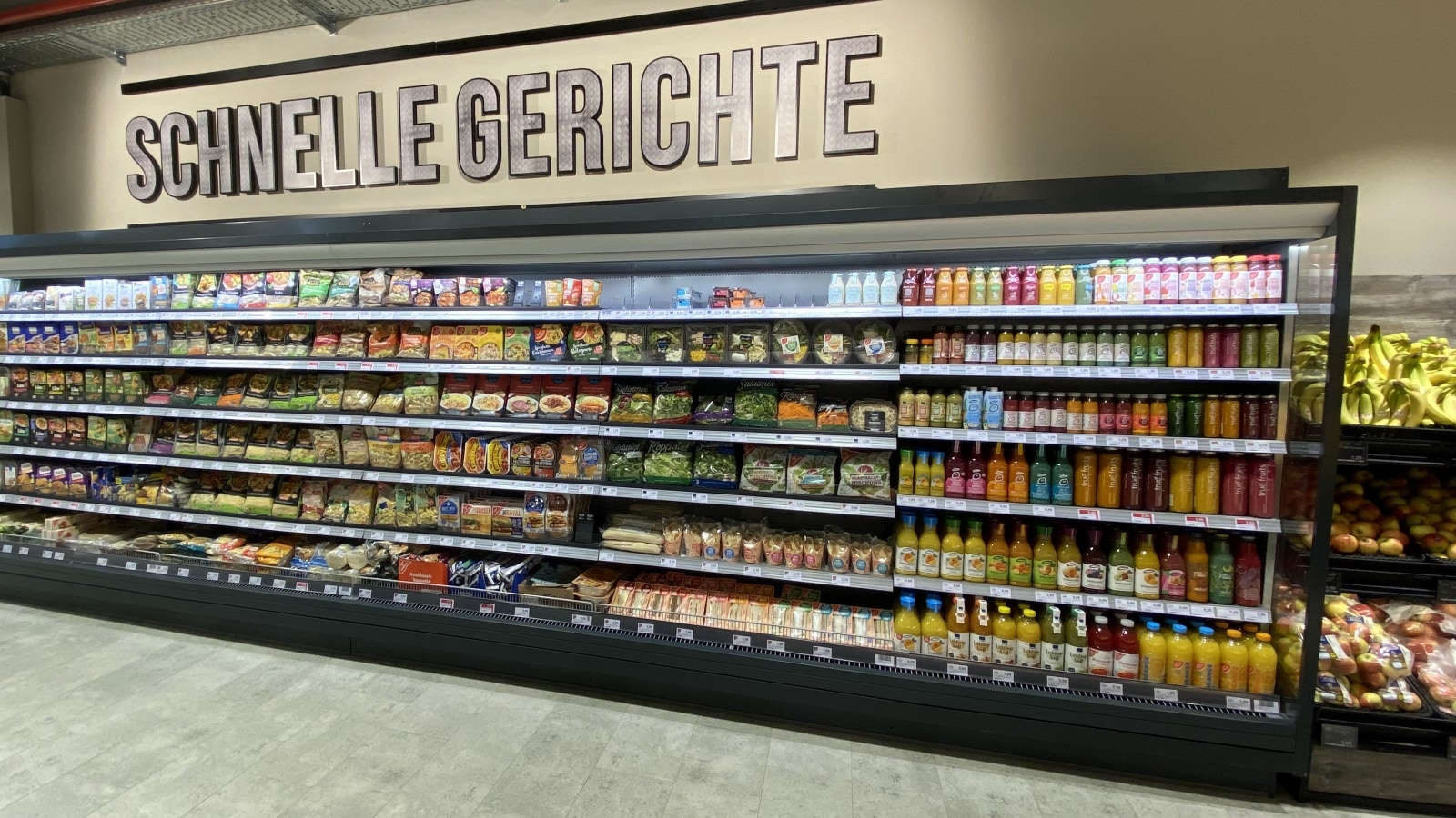 Kühlregal mit Convenience-Produkten über dem der Text "Schnelle Gerichte" steht. 